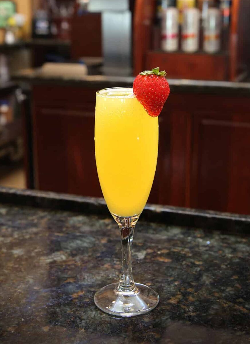 Mimosa cocktail garnished with a fresh strawberry, set on the bar at Tavern at Park.
