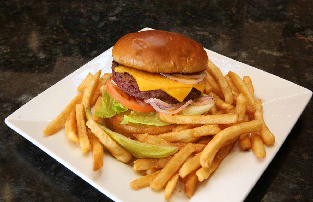 Half-Pound Classic Angus Burger on a brioche bun with cheese, lettuce, tomato, onion, and a side of french fries.