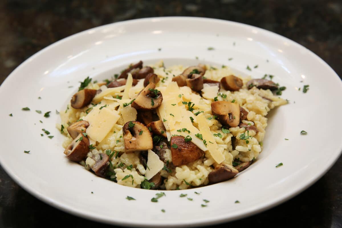 Mushroom Risotto featuring creamy Arborio rice mixed with sautéed mushrooms and topped with shaved parmesan cheese.