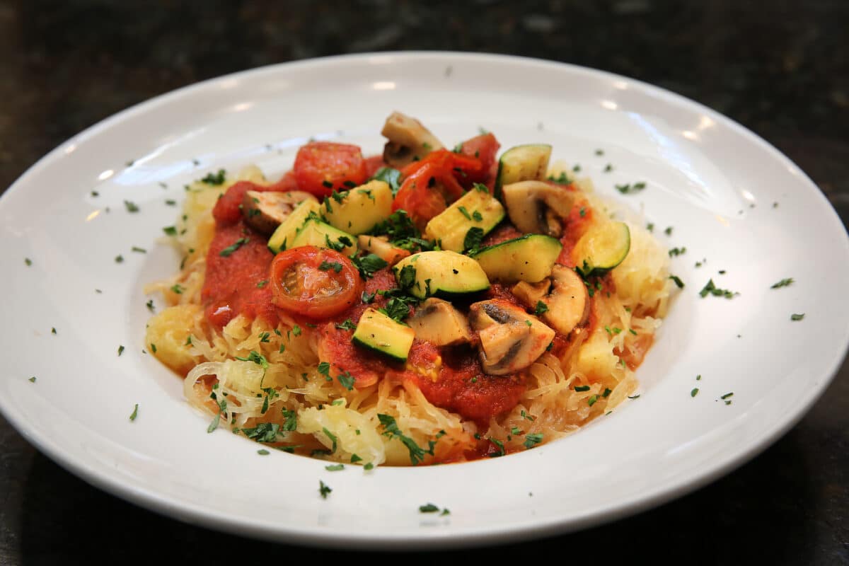 Spaghetti Squash Marinara topped with roasted summer vegetables like zucchini and mushrooms, in a rich marinara sauce.