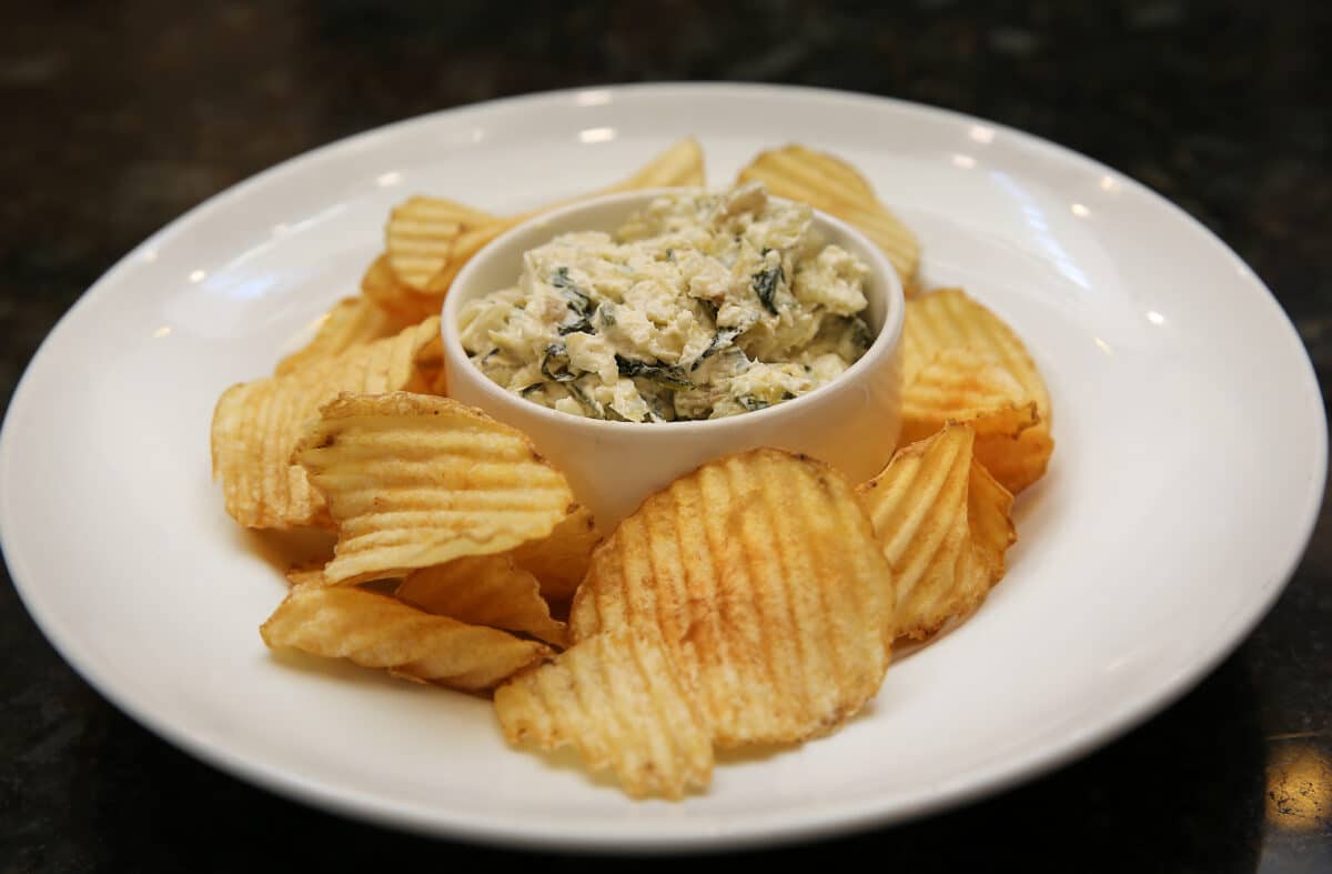 Warm Spinach Artichoke Dip appetizer featuring baby spinach and artichoke, served with house-made ruffled potato chips.